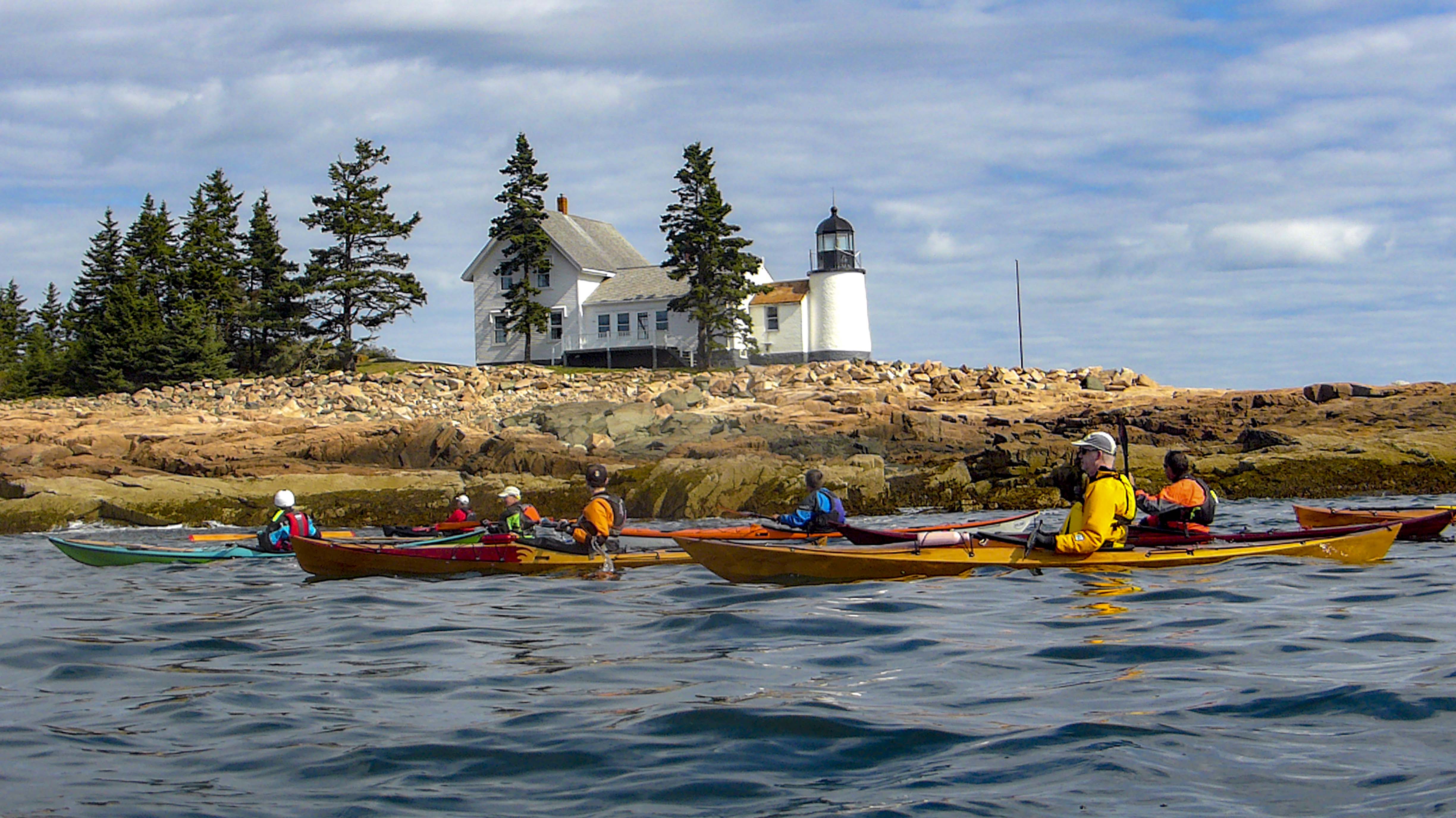 sea kayaking past a light house in maine