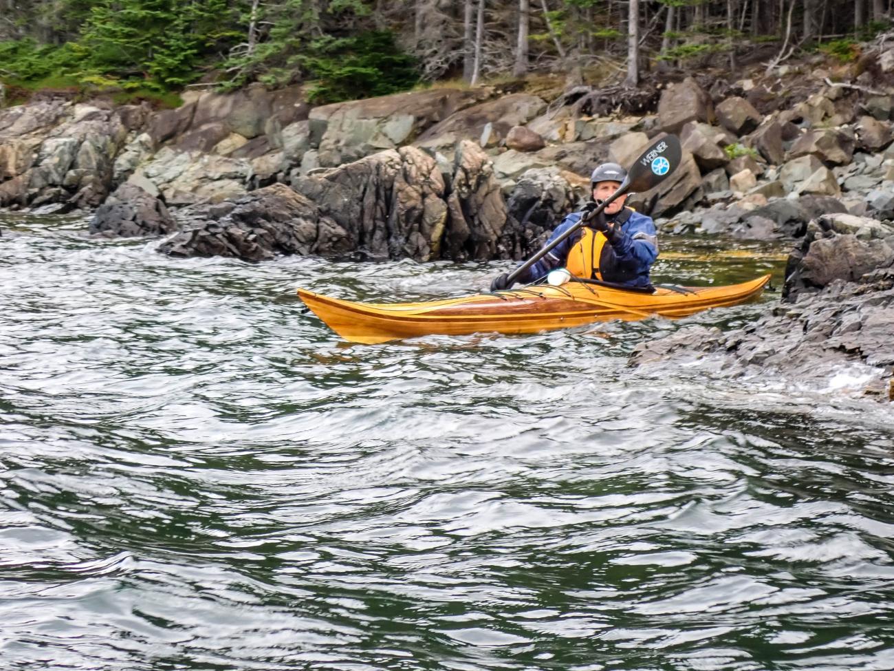 paddling a wooden kayak on the coast of Maine